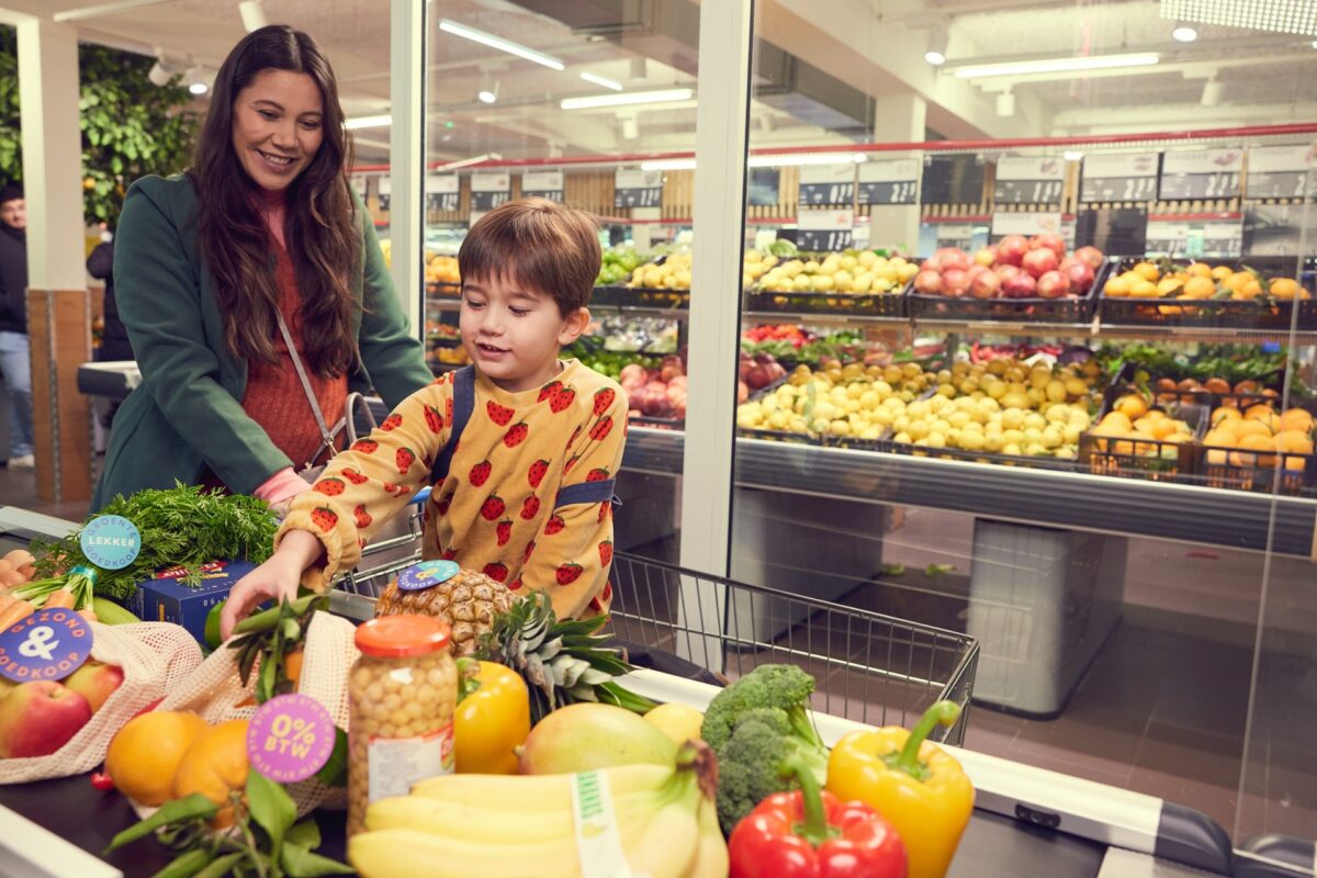 Moeder en kind in de supermarkt bij de kassa om gezonde producten af te rekenen.